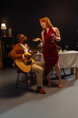 Fototapeta premium Musician playing acoustic guitar for elegant woman during romantic dinner