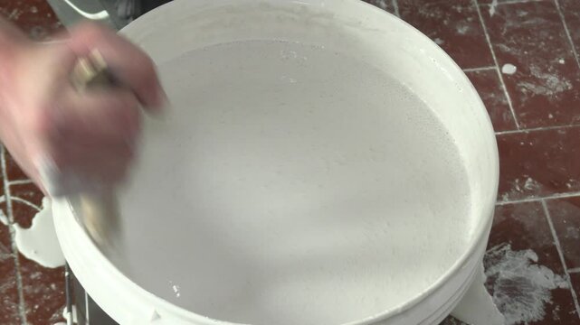 m&eacute;lange de peinture blanche dans un pot