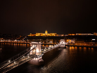 Fototapeta premium Széchenyi Chain Bridge connecting Buda and Pest at night with Buda Castle illuminated Aerial view