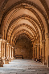Ancient monastery cloister in Porto, Portugal, featuring arched stone corridors and intricate columns bathed in warm sunlight. Stunning medieval architecture and historical atmosphere. 