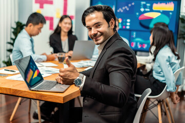 Portrait of businessman or analyst looking at camera with his colleague analyzing data analysis in dynamic business strategy investment planning meeting. Meticulous