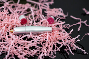 Permanent makeup. A silver permanent machine on a pink and black background. Close-up.