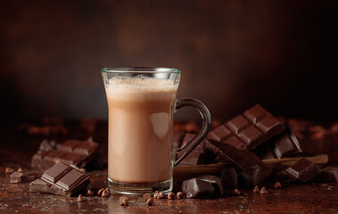 Hot chocolate cocoa drink in glass mug and pieces of  bitter chocolate.