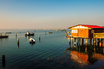 winter sunset over the Scardovari lagoon with fishing boats and cabins inside the delta of the...