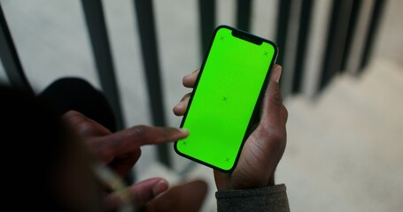 A mobile with a green screen in the hand of a man of African American appearance scrolling the screen, close-up, video filming from behind. Copy space, mockup, chroma key. Video in 4k, red komodo