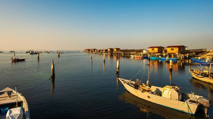 winter sunset over the Scardovari lagoon with fishing boats and cabins inside the delta of the...