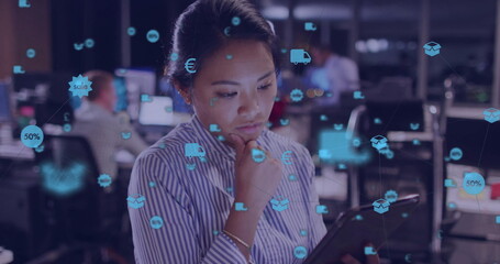 Image of network of connections with icons over biracial businesswoman using tablet in office