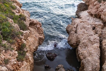 Fototapeta premium Majestic cliffs on coast of Portugal, washed by the endless ocean in the rays of the sunset. golden light of the sun paints rocks in warm shades, emphasizing their texture and creating long shadows. 