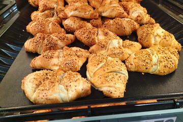 Fresh sesame covered croissants on a bakery shelf. Golden brown pastry with a crispy texture. Delicious baked goods displayed in a store. Breakfast tasty snack.