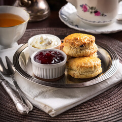 A classic British tea setup with scones, clotted cream, and jam