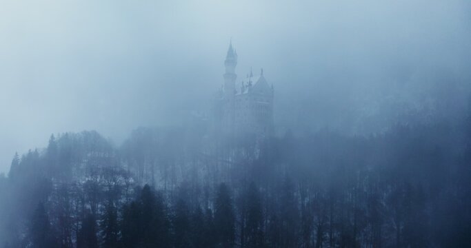 Hohenzollern Castle on a foggy winter day. Video footage from a quadcopter approaching the castle, located on top of a snow-covered hill. Germany