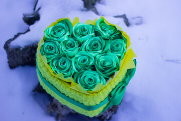 A blazing heart of scarlet roses in a festive box tied with a bow, against the backdrop of winter frost