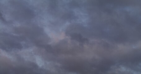 Obraz premium View of the sky covered with gray clouds with a pink reflection of the setting sun. Video in 4 k, red komodo.