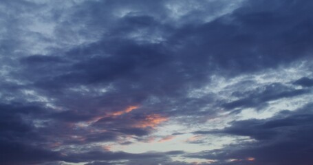 Fototapeta premium Dark cumulus obscures pink clouds illuminated by the setting sun. Sky at sunset. Video in 4k, red komodo.