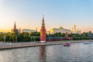 Fototapeta premium View of Kremlin with Vodovzvodnaya tower, Grand Kremlin Palace from repaired Bolshoy Kamenny Bridge in Moscow city on sunny summer day. Cruise ship sails on the Moscow river