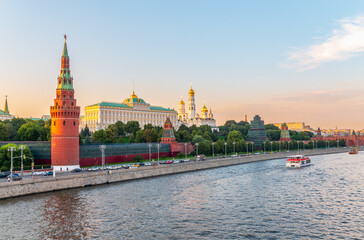 Obraz premium View of Kremlin with Vodovzvodnaya tower, Grand Kremlin Palace from repaired Bolshoy Kamenny Bridge in Moscow city on sunny summer day. Cruise ship sails on the Moscow river