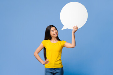 Nice Idea. Pensive asian woman holding and looking up at blank speech bubble with empty space for...