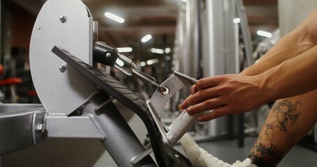Close-up of a young man's hand pulling on the handrail of an exercise machine, lifting weights. Strength training in a modern gym