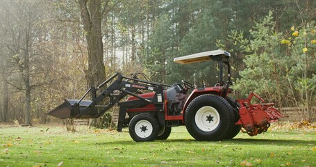 A modern agricultural tractor with a canopy above the driver's seat stands on a farm on an autumn sunny day, there are no people in the video