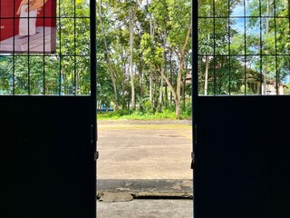 Wide open doors reveal lush greenery outside an indoor space during a bright sunny day