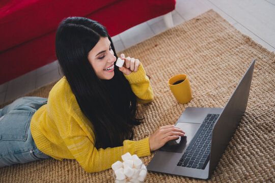 Young woman relaxing at home enjoying leisure time with laptop and cup of coffee - Powered by Adobe