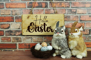 Hello Easter text with Easter eggs with rabbit doll and wooden signboard space for text message on old brick wall background