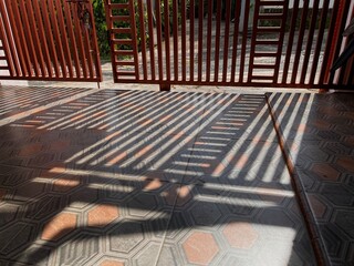 Shadows cast by wooden gate on tiled floor during sunny afternoon