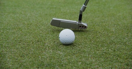 A golf club hits a ball, close-up, no people. Details of playing golf on an artificial surface