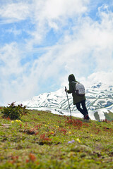 Woman hiker in the green and snow mountains