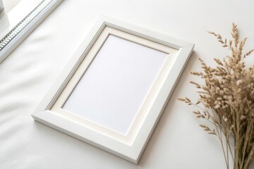 Minimalist White Photo Frame Resting on a Clean Surface Surrounded by Dried Flowers