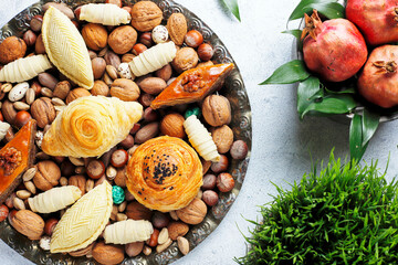 Traditional Azerbaijan holiday Novruz background with green semeni,traditional azerbaijan sweets,shekerbura,qogal,paxlava,mutaki and different nuts and sweets,top view,space for copy