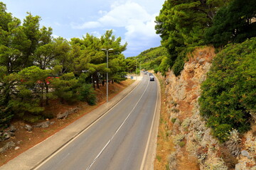 Mountain road in Croatia among high mountains, hills, pine forest. Cars drive on Croatian highway, autobahn