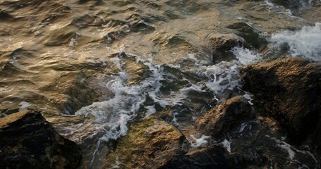 Sea water with foam waves hits the coastal rocks, splashing beautifully and washing the boulders. 4k video, red komodo