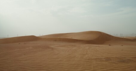 The wind inflates the sands of the desert, forming a beautiful sandy pattern. Desert sand dunes. Power lines in the background. 4k video, red komodo