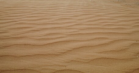 Top view of the sandy waves of the desert. The wind carries fine sandy dust. No people. Sand patterns. 4k video, red komodo
