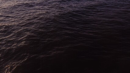 Drone flies over dark sea water. Small waves, top view. Quadcopter video, no land, only water.