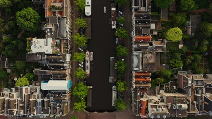 Top view of the Amsterdam canal between the streets with beautiful old traditional houses. Ships...