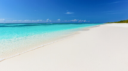 Obraz premium Scenic view of pristine tropical beach with soft white sand crystal-clear turquoise water and deep blue sky. Summer vacation, exotic travel destination, island getaway, ocean relaxation, beach holiday