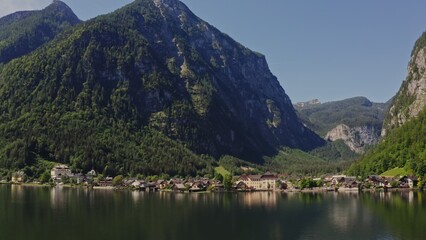 Fototapeta premium Non-white village with traditional houses, located on the shore of a picturesque lake, in a lowland between the Alps. Austria, Hallstatt, drone video