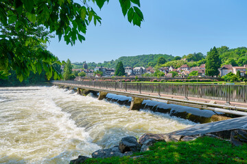 Weir and bridge over the Dordogne at Beaulieu-sur-Dordogne and the Dordogne river in Corrèze Nouvelle-Aquitaine in Southern France on a sunny day in summer  