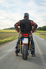 Motorradfahrer auf seiner Maschine von hinten, labelfrei und retuschiert.