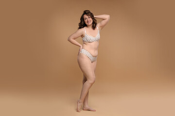 Fototapeta premium Beautiful woman in underwear on dark beige background. Cellulite problem