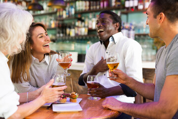 Diverse people talking and laughing drinking beer at a bar table