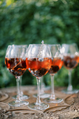 Cocktails with wine and floating blueberries stand on a wooden table in the garden
