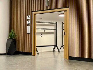 Modern cloakroom entrance with wooden panel walls and a minimalist design. The space features...