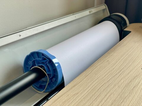 Paper roll installed in a plotter printer, with a visible mounting mechanism
