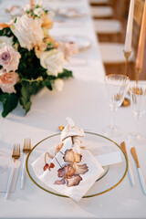 Blank invitation lies near a knotted napkin on a plate on a holiday table
