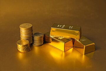 Gold bars and coins on shiny background