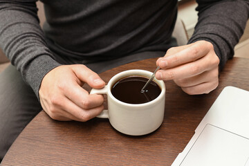 Man having coffee break at wooden table in cafe, closeup