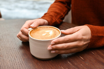 Woman having coffee break at wooden table in cafe, closeup